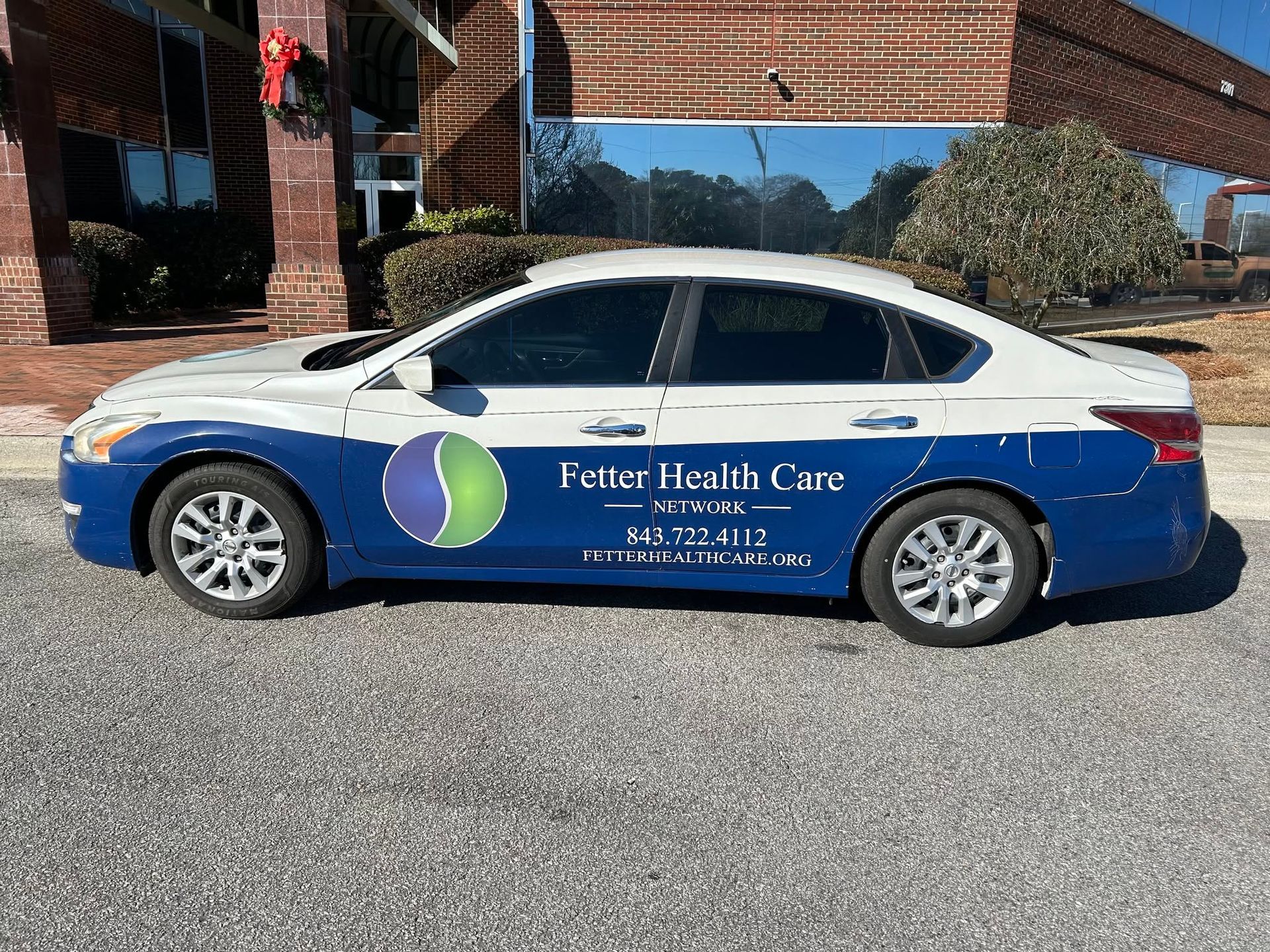 White and blue Future Health Care car parked outside a brick building