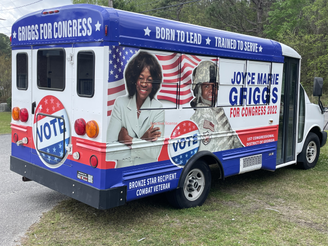 Campaign bus parked on grass, wrapped with Joyce M. Griggs for Congress, vote signs, and American flag graphics