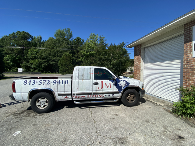 White service pickup truck parked by a building, with 