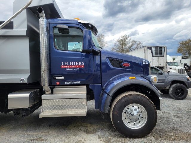 Blue dump truck parked in a gravel lot under cloudy skies