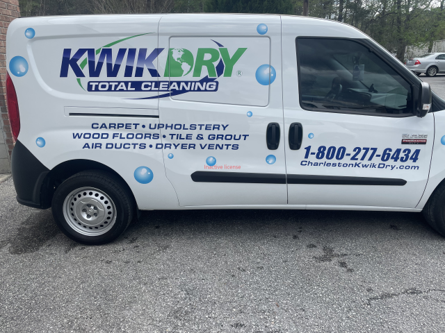 White Kvik Dry Total Cleaning van with company logo, phone number, and service list parked on a street.