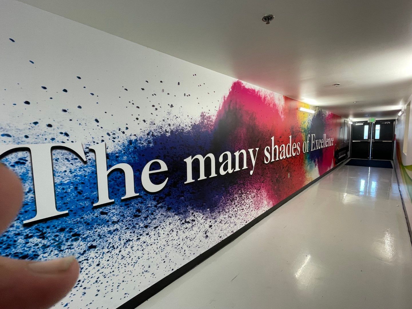 Hallway wall mural reading “The many shades of…” with blue and pink paint-splash design
