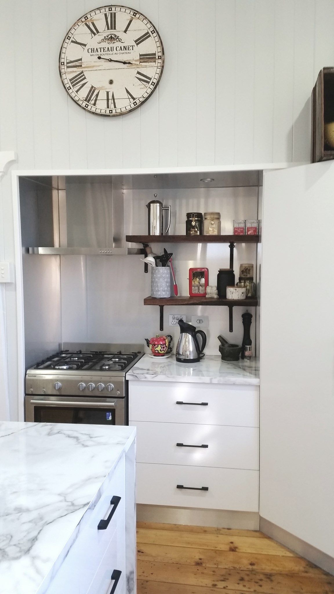 Kitchen Nook With Stove, Shelves, and a Marble Countertop, Topped With a Clock — Payton Kitchens In Wilsonton, QLD
