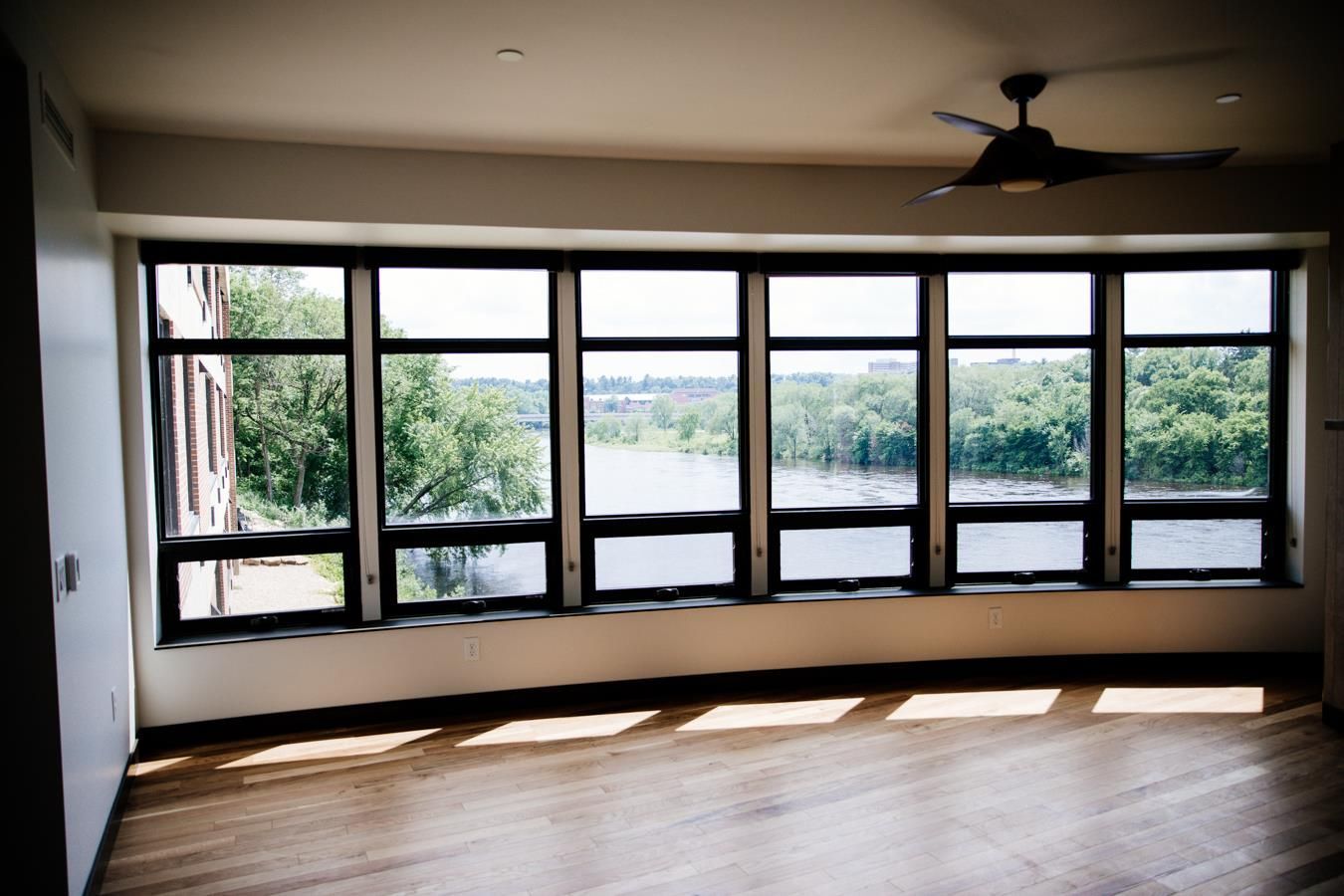 An empty room with a lot of windows and a ceiling fan