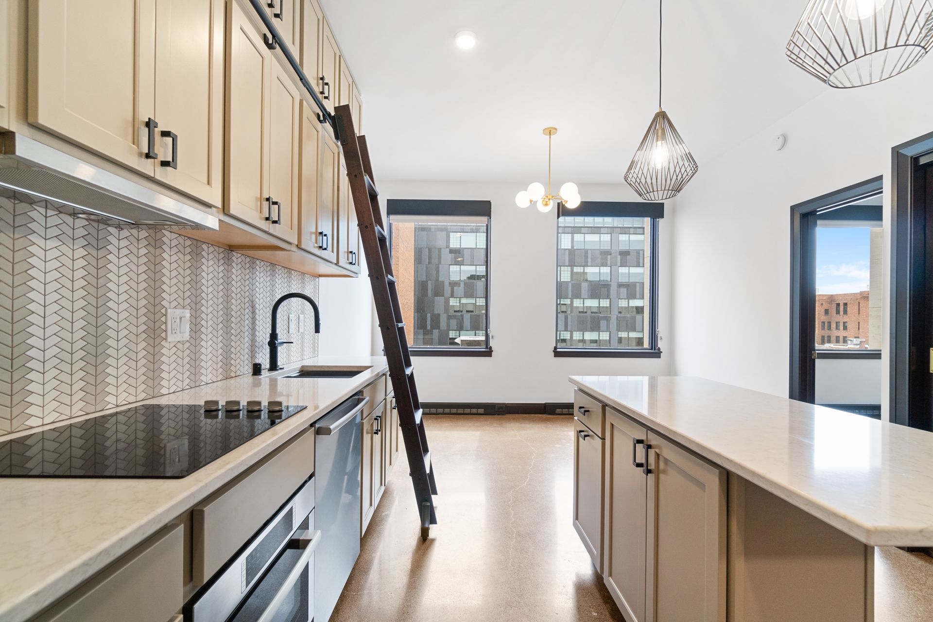 Modern kitchen with light cabinets, island, ladder, and city views.