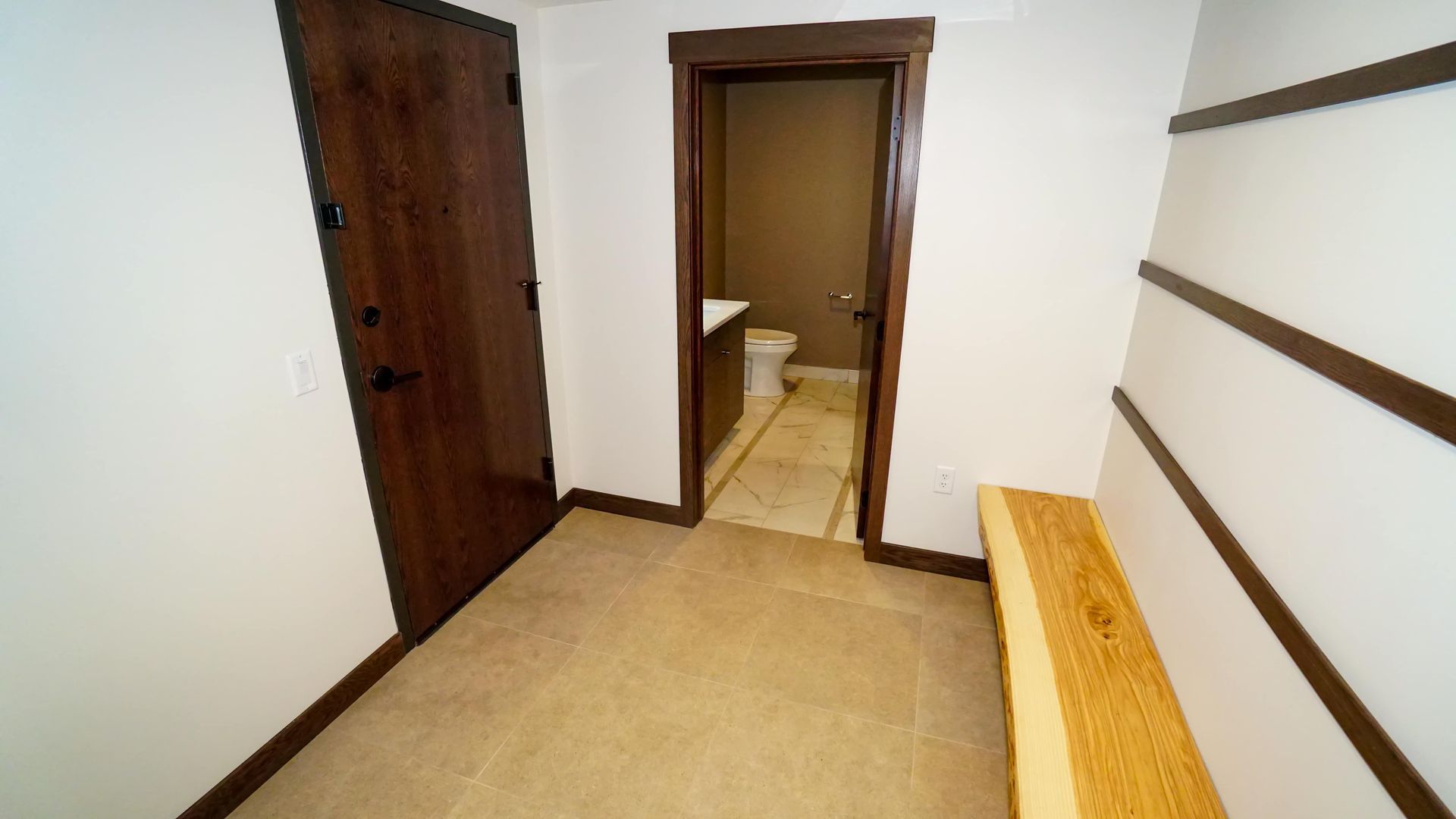 A hallway with a wooden door leading to a bathroom.