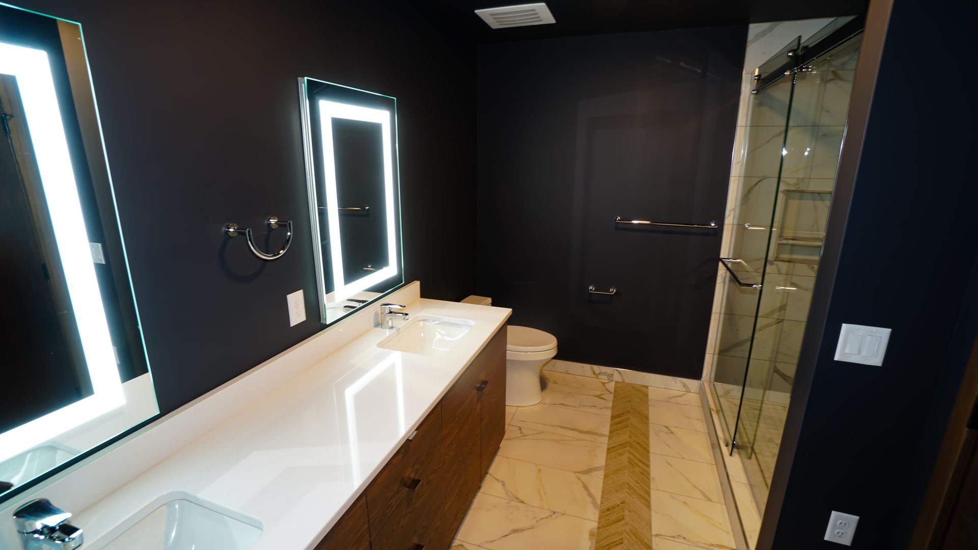 A bathroom with two sinks , a toilet and a shower.