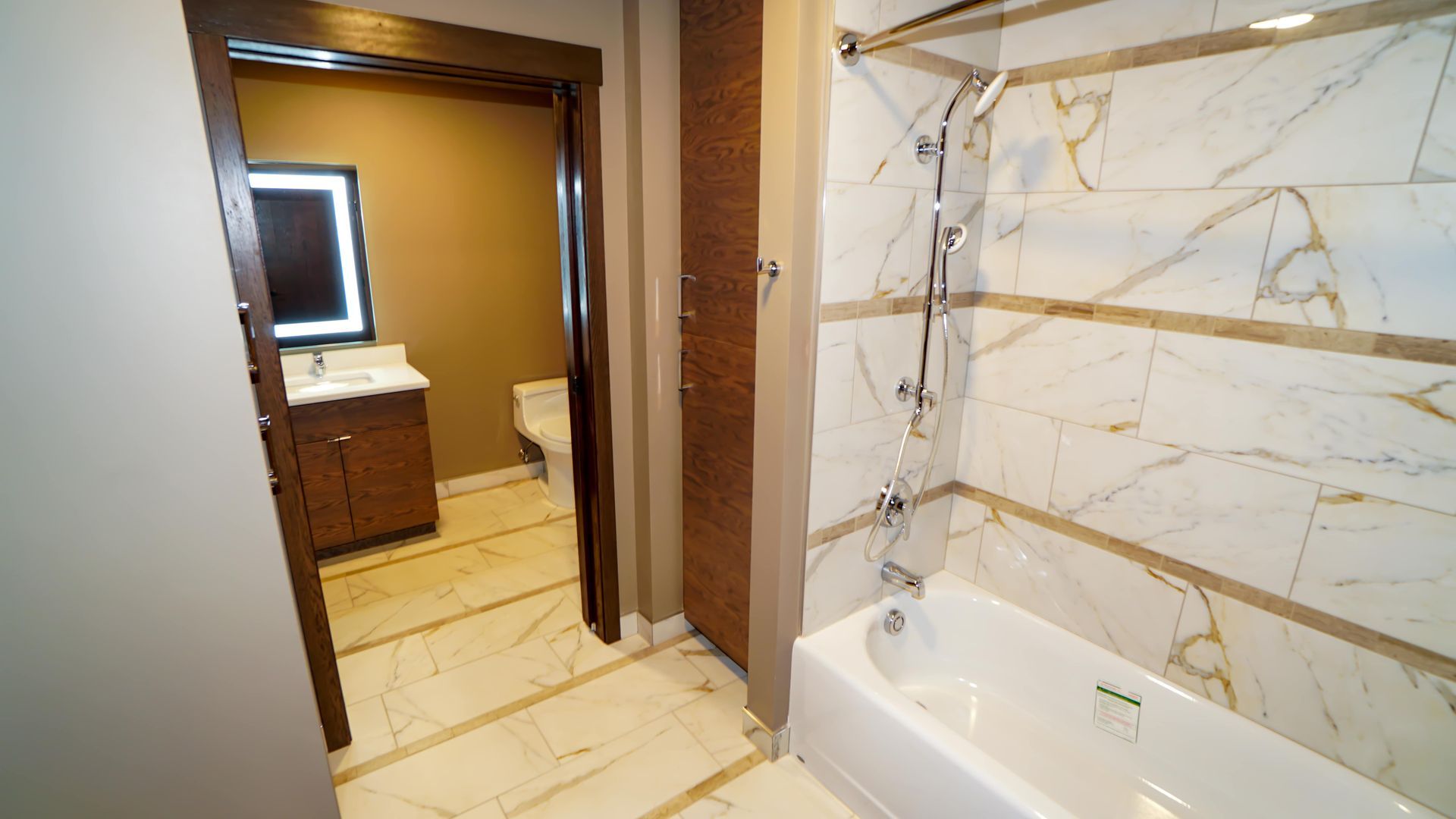 A bathroom with a tub , sink , toilet and mirror.