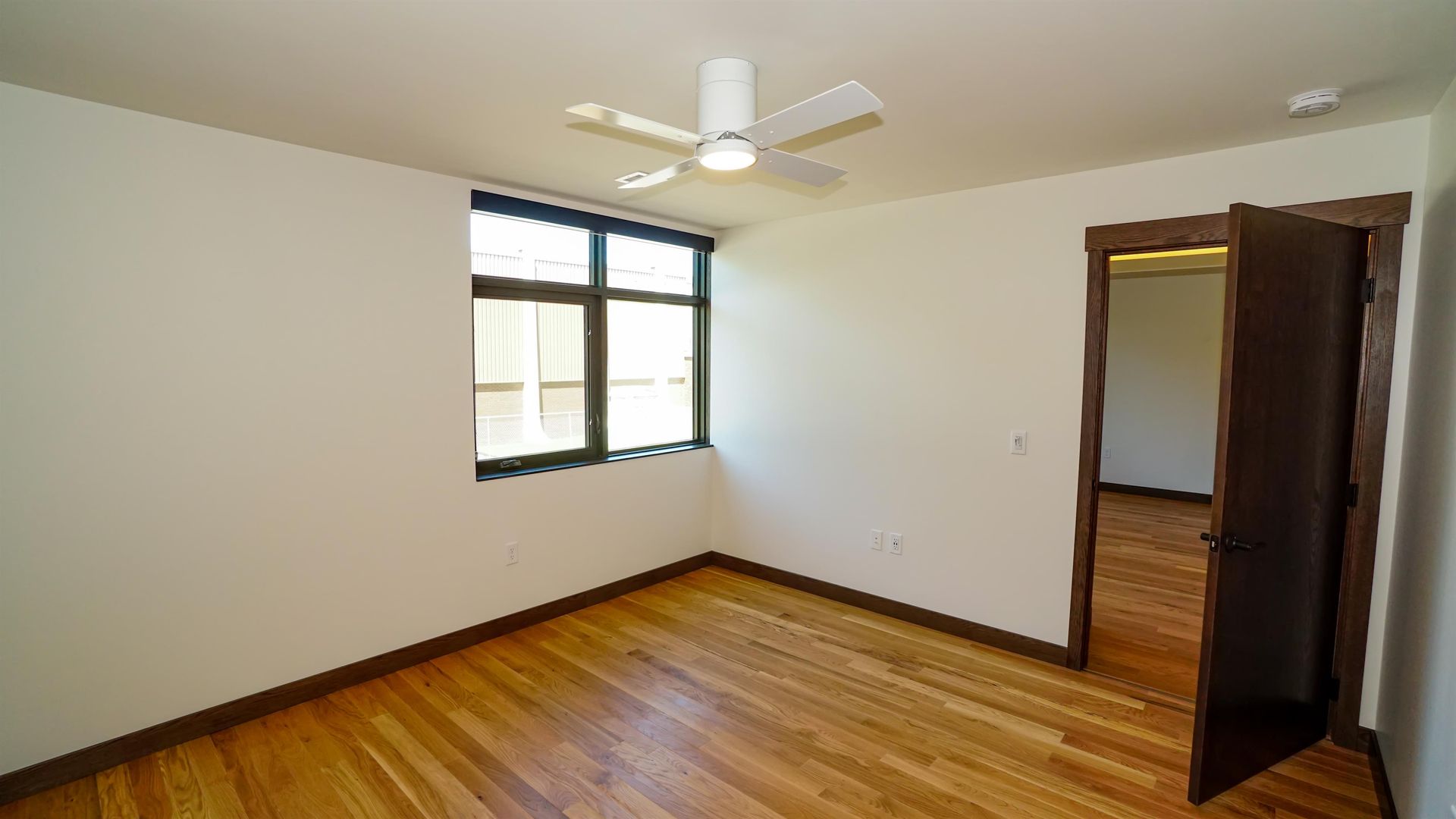An empty room with hardwood floors and a ceiling fan.