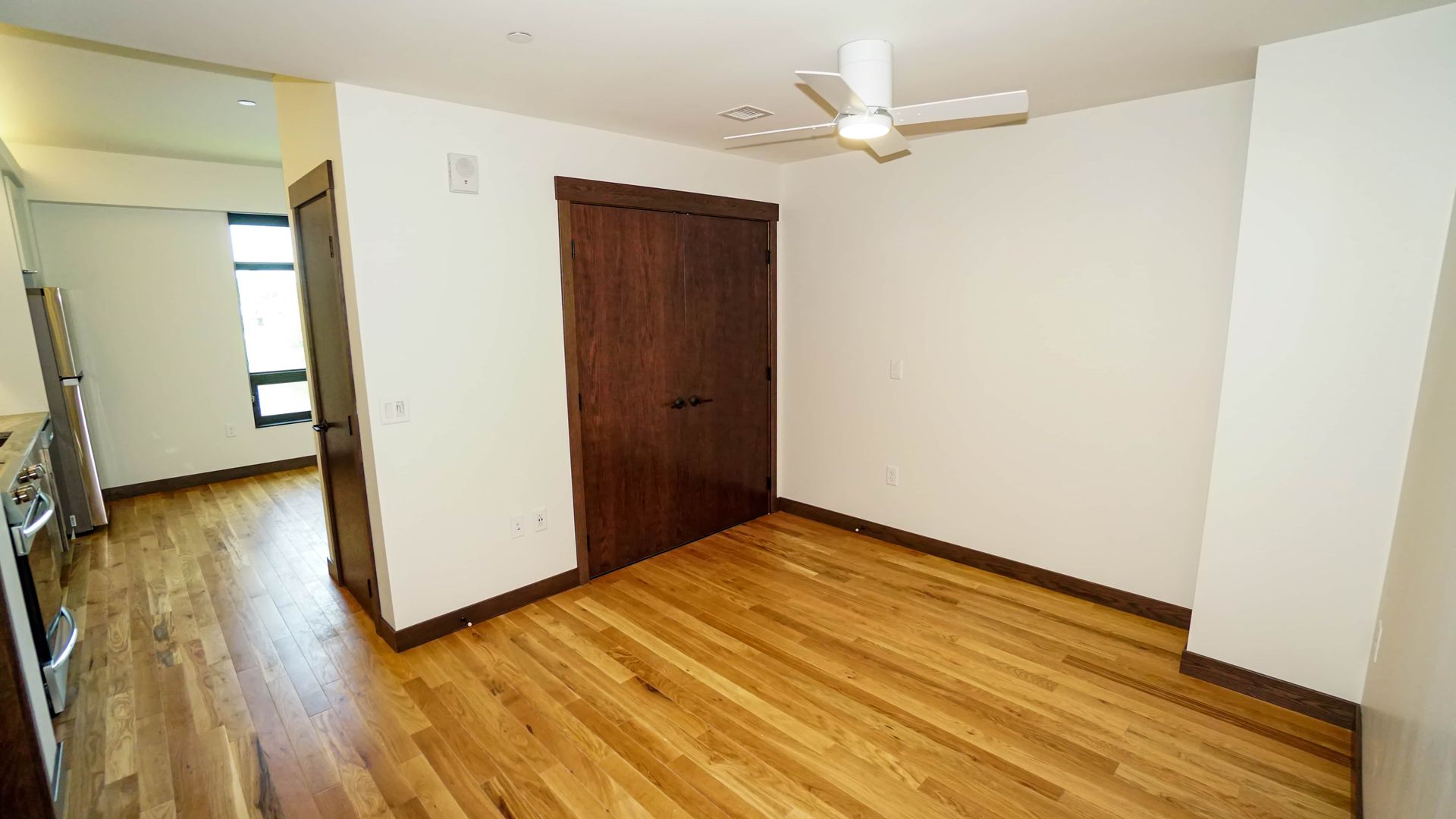 An empty room with hardwood floors and a ceiling fan.