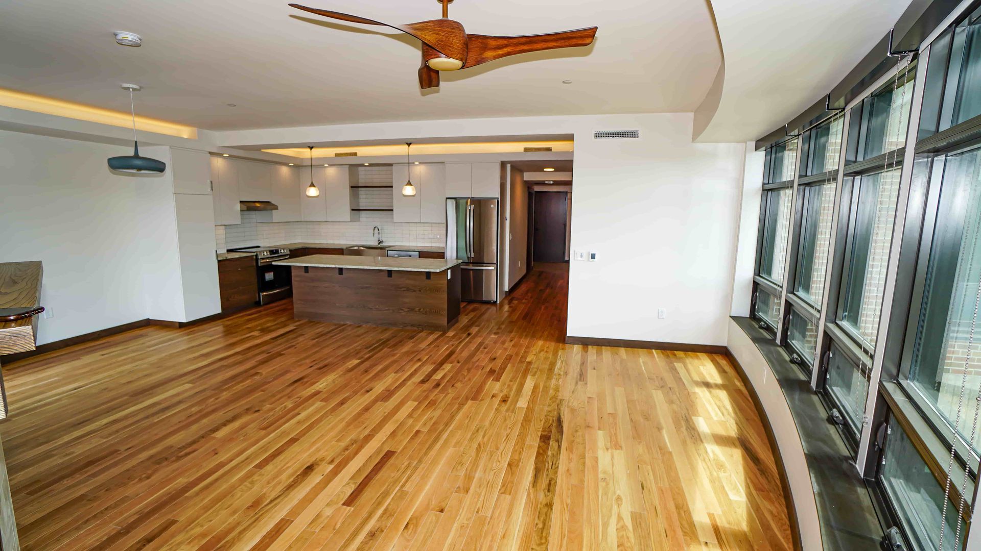 An empty room with hardwood floors and a ceiling fan