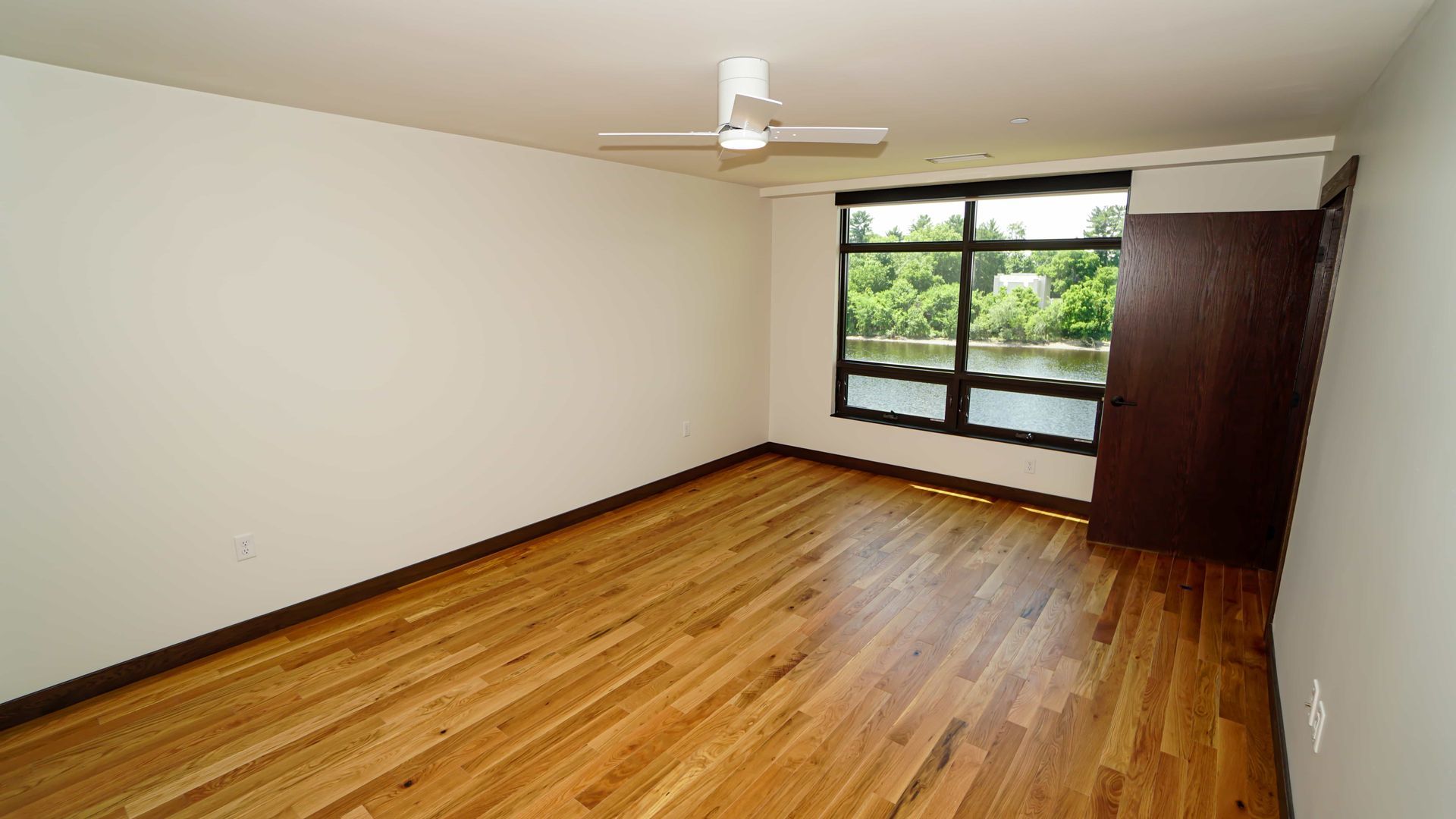 An empty room with hardwood floors and a ceiling fan