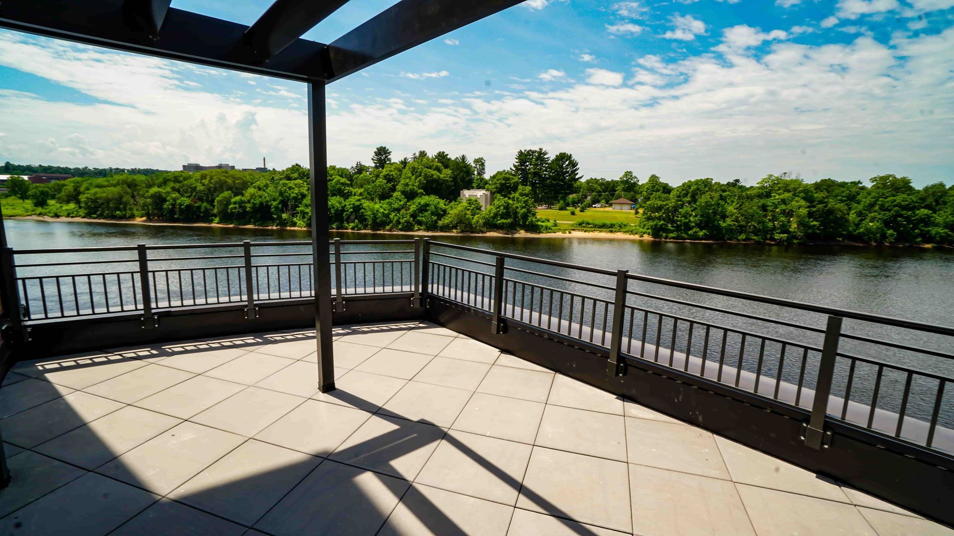 A balcony with a view of a river and trees.