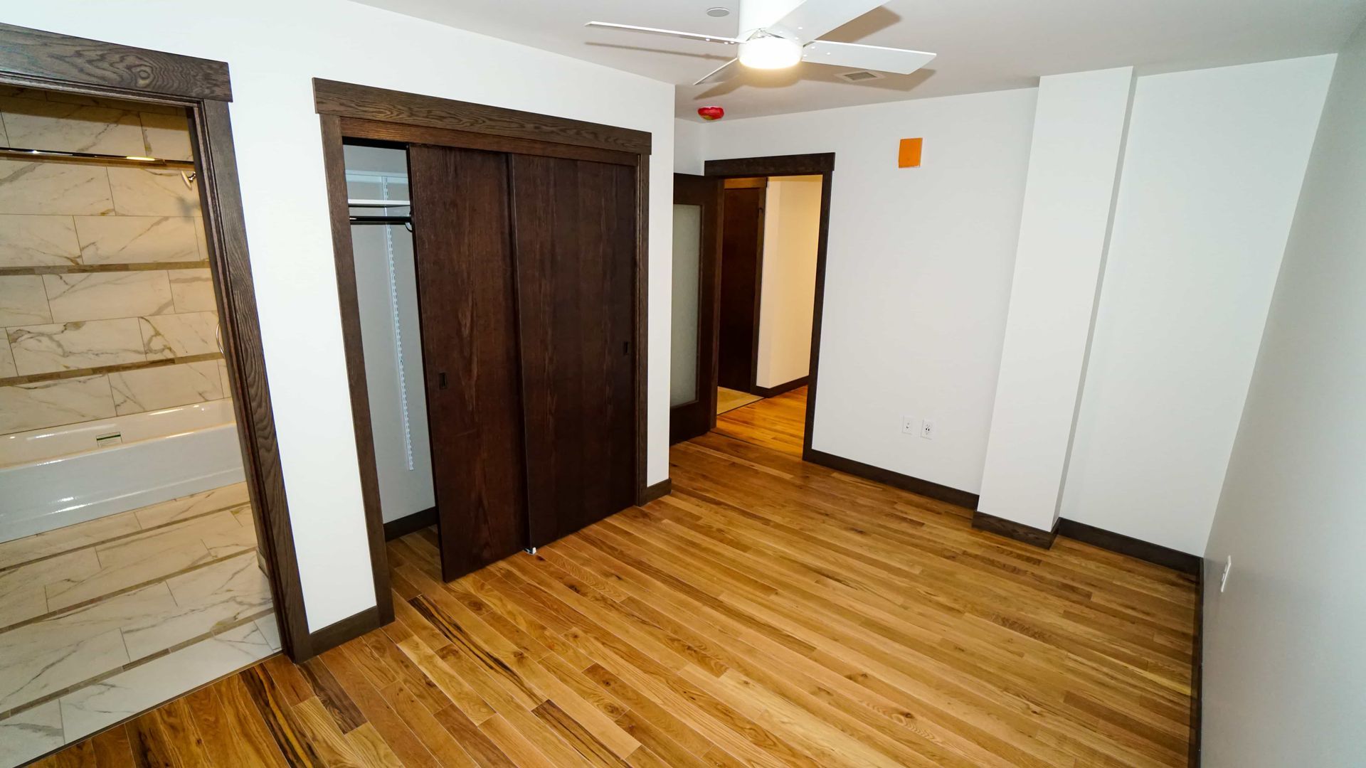 An empty room with hardwood floors and a ceiling fan.
