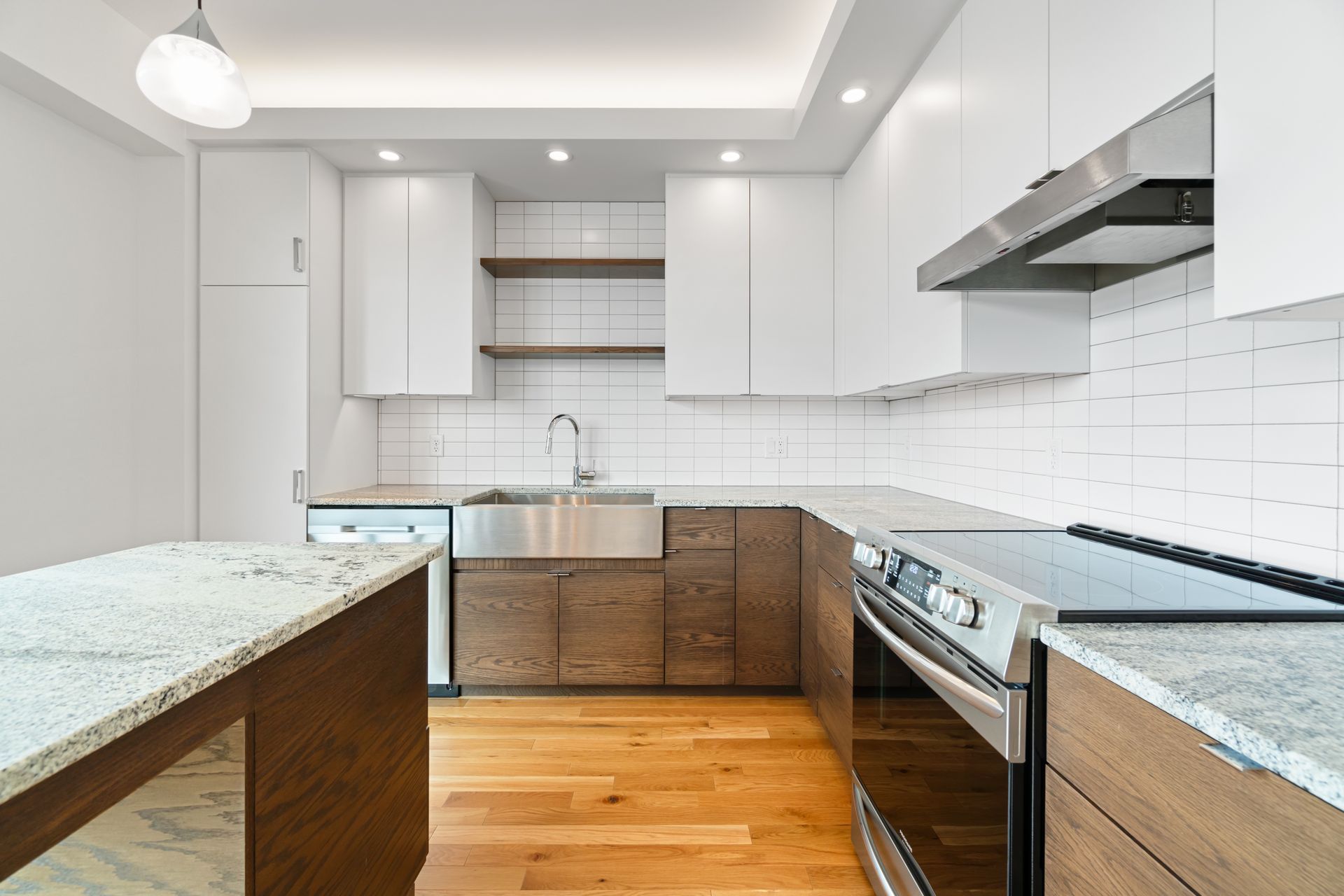 Modern kitchen with white and wood cabinets, stainless steel appliances, and granite countertops.