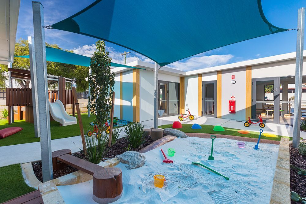 A sandbox with a slide and umbrellas in a playground at Thornlie Early Learning Centre.