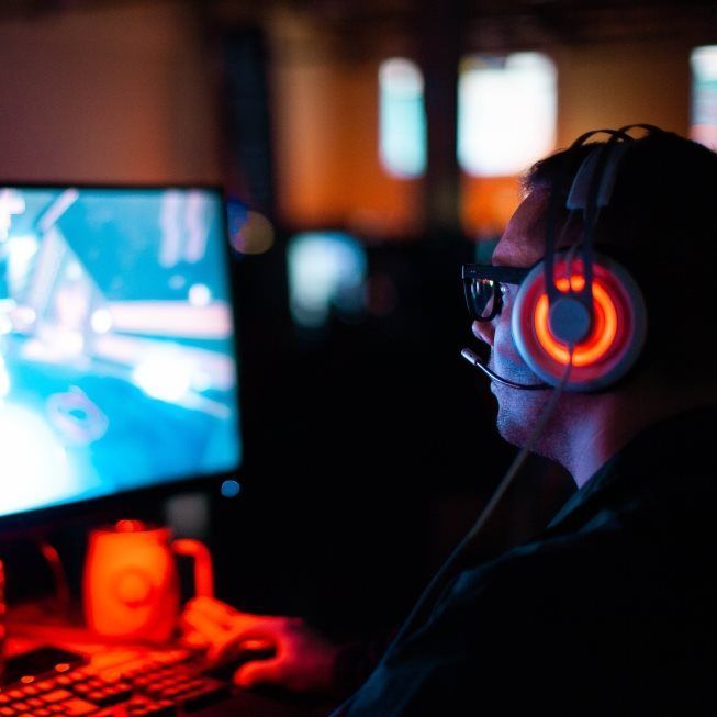 A man wearing headphones is playing a video game on a computer