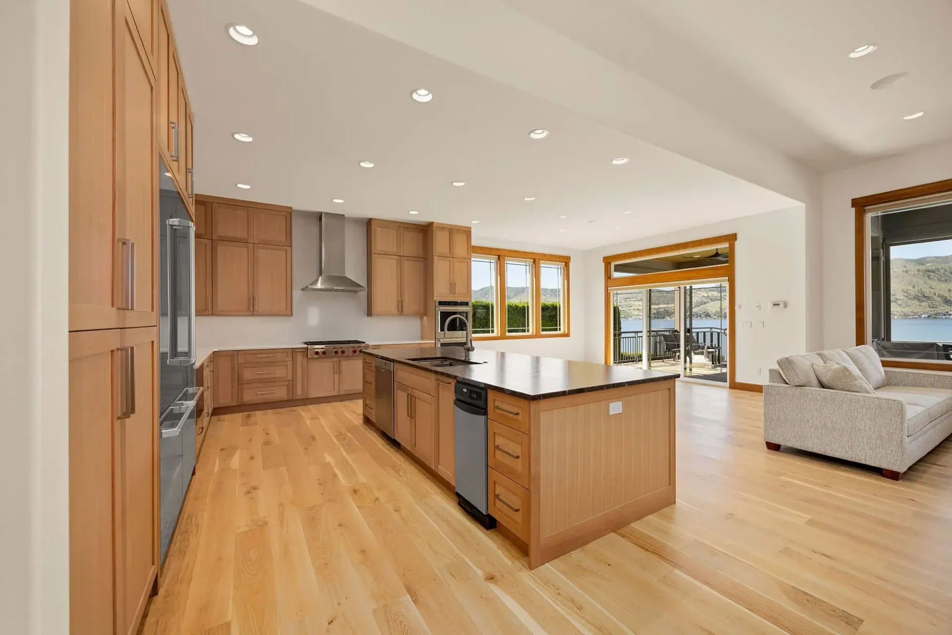 Spacious kitchen with wood cabinets, island, and hardwood floors. Open to living area with sliding door.