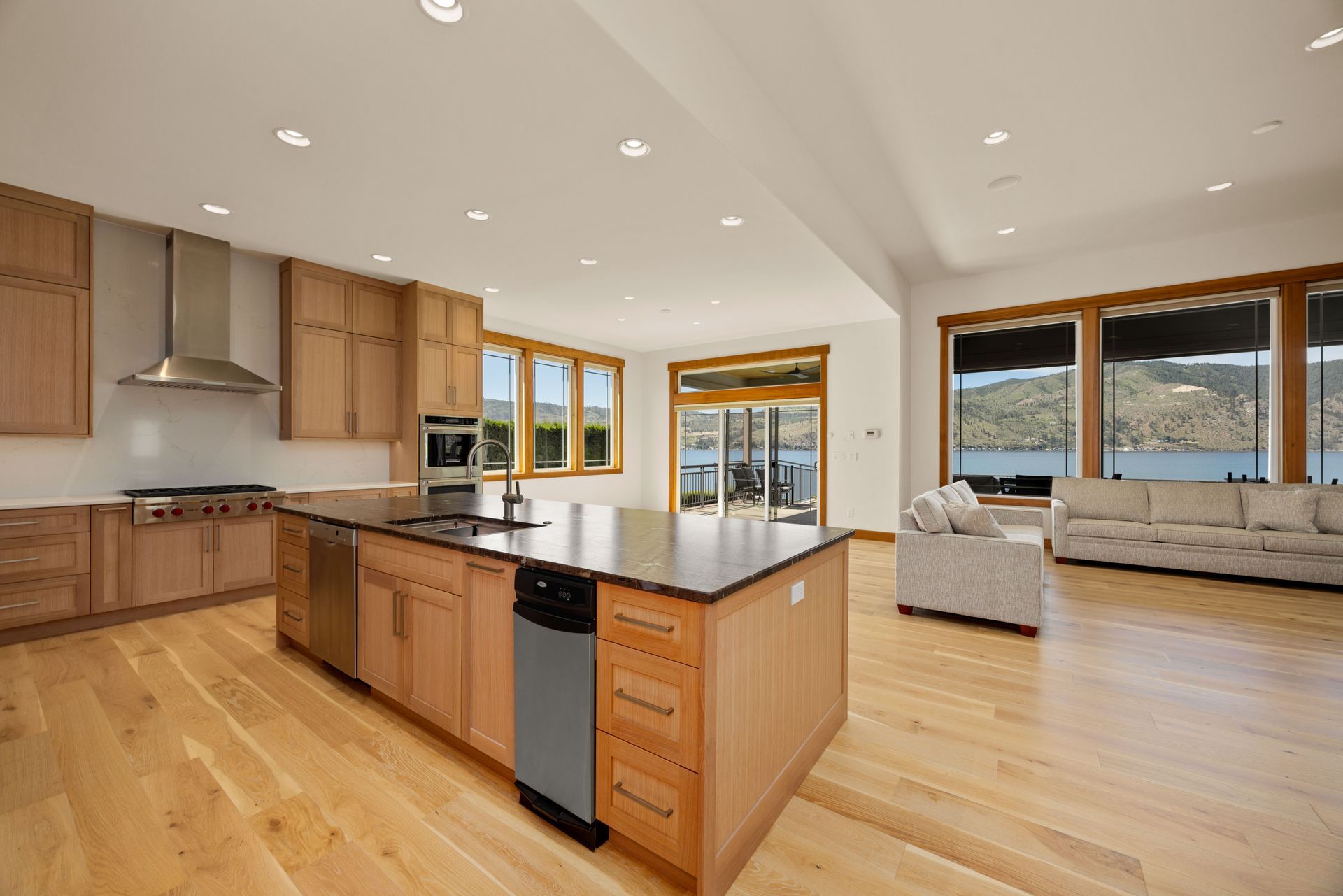 Spacious kitchen with wood cabinets, island, and large windows overlooking a lake.