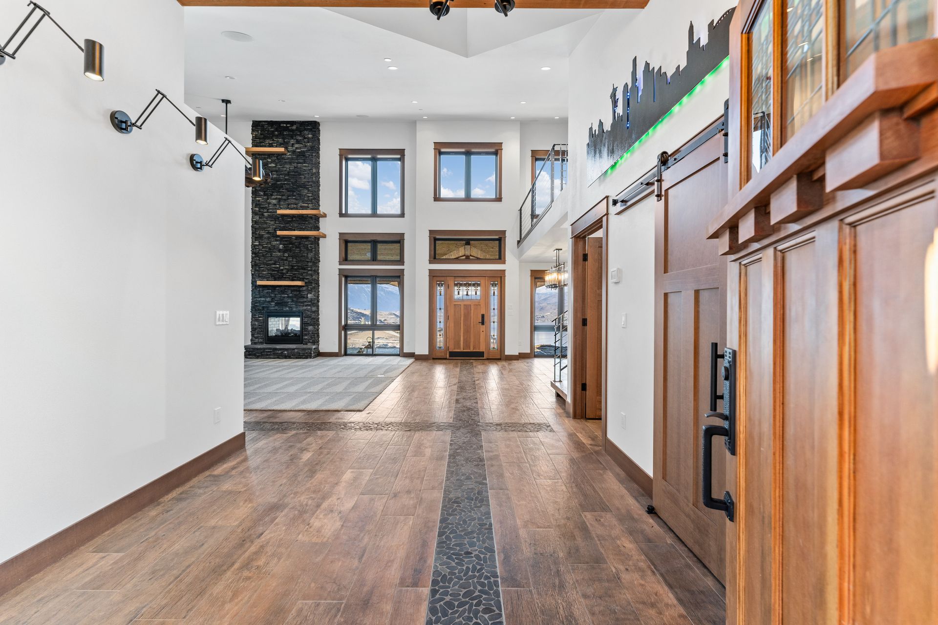 Hallway of a modern home with wood floors, stone fireplace, and barn door.