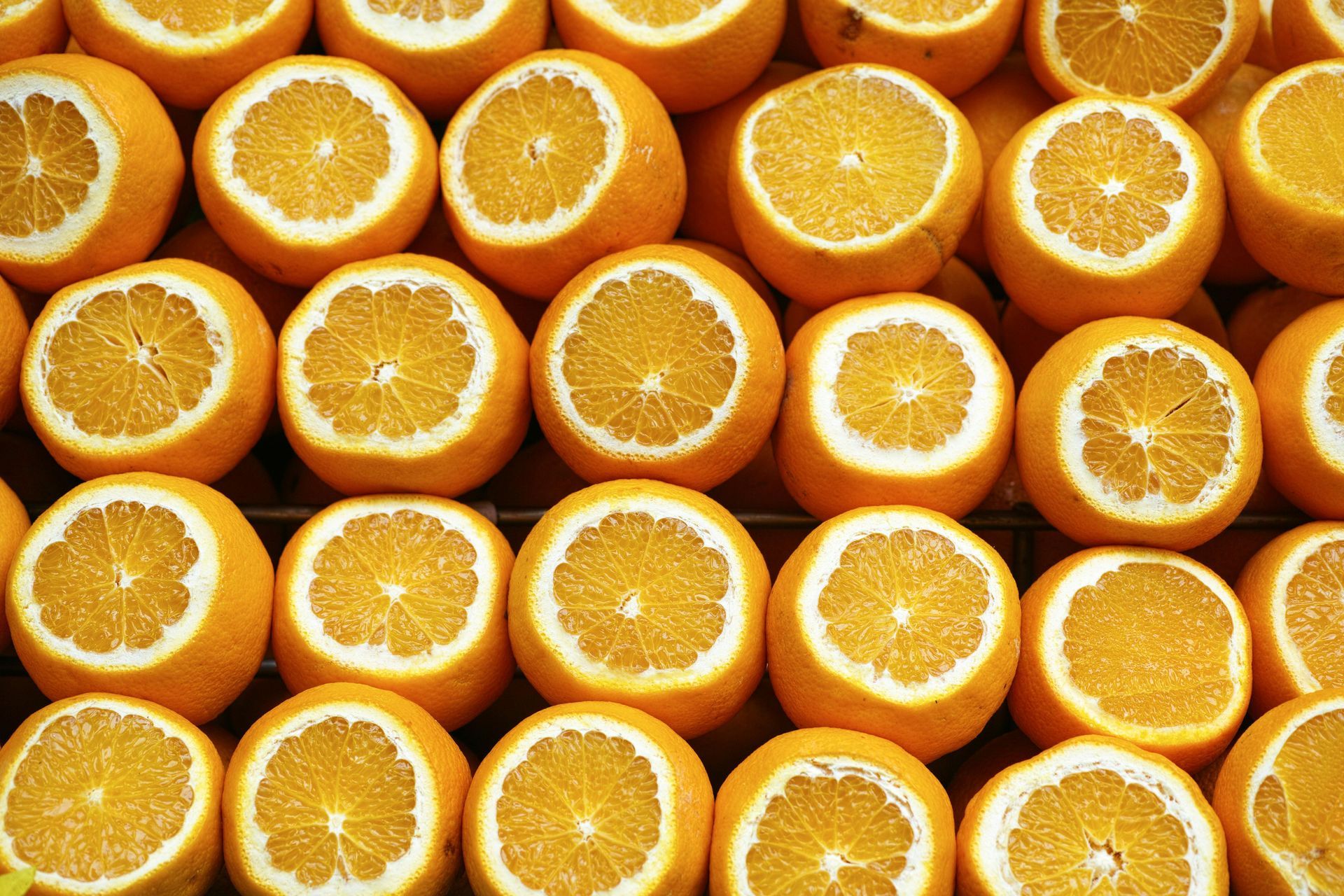 Rows of sliced oranges, showing bright orange flesh and white rind.