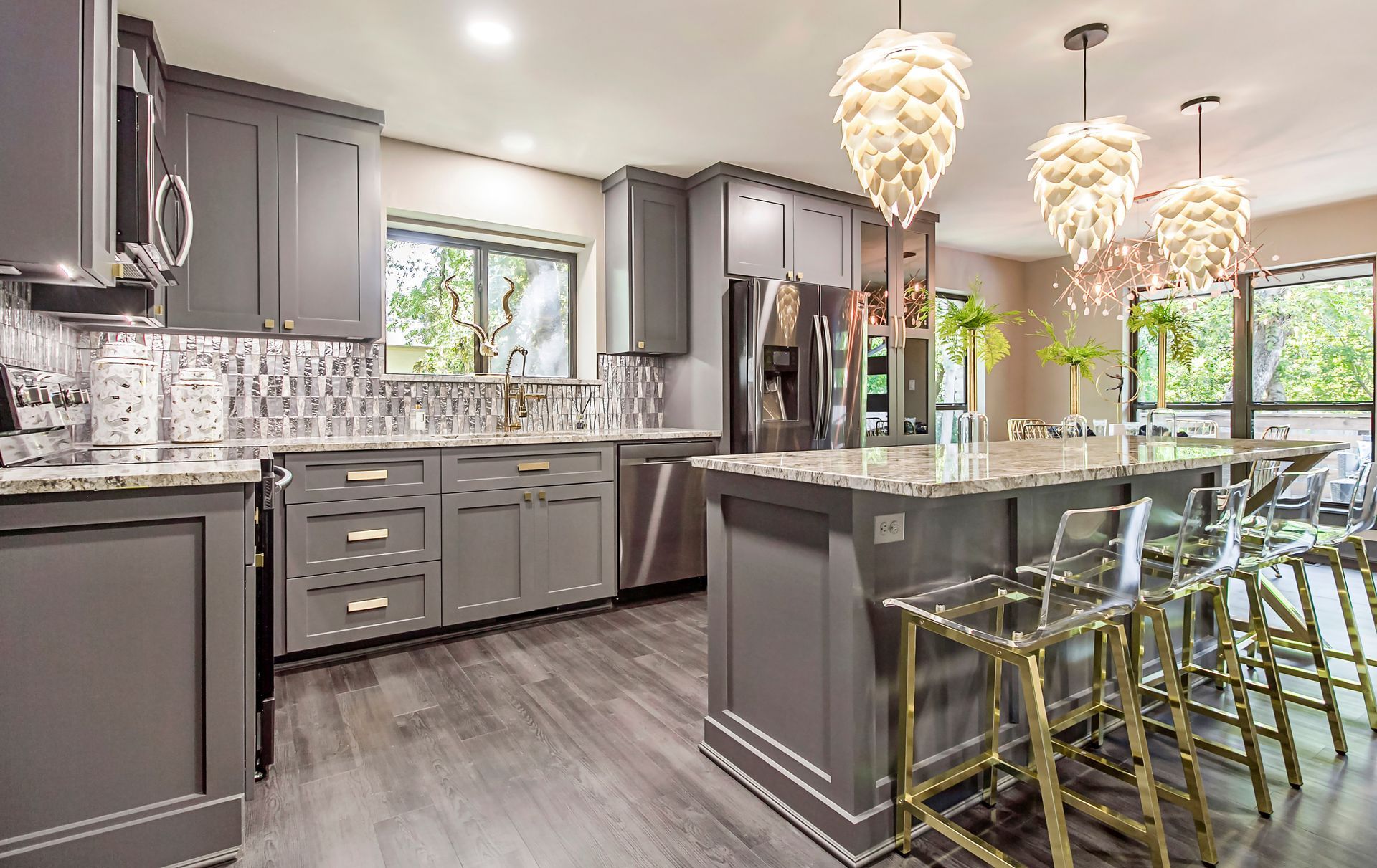 A kitchen with gray cabinets and stainless steel appliances and a large island.
