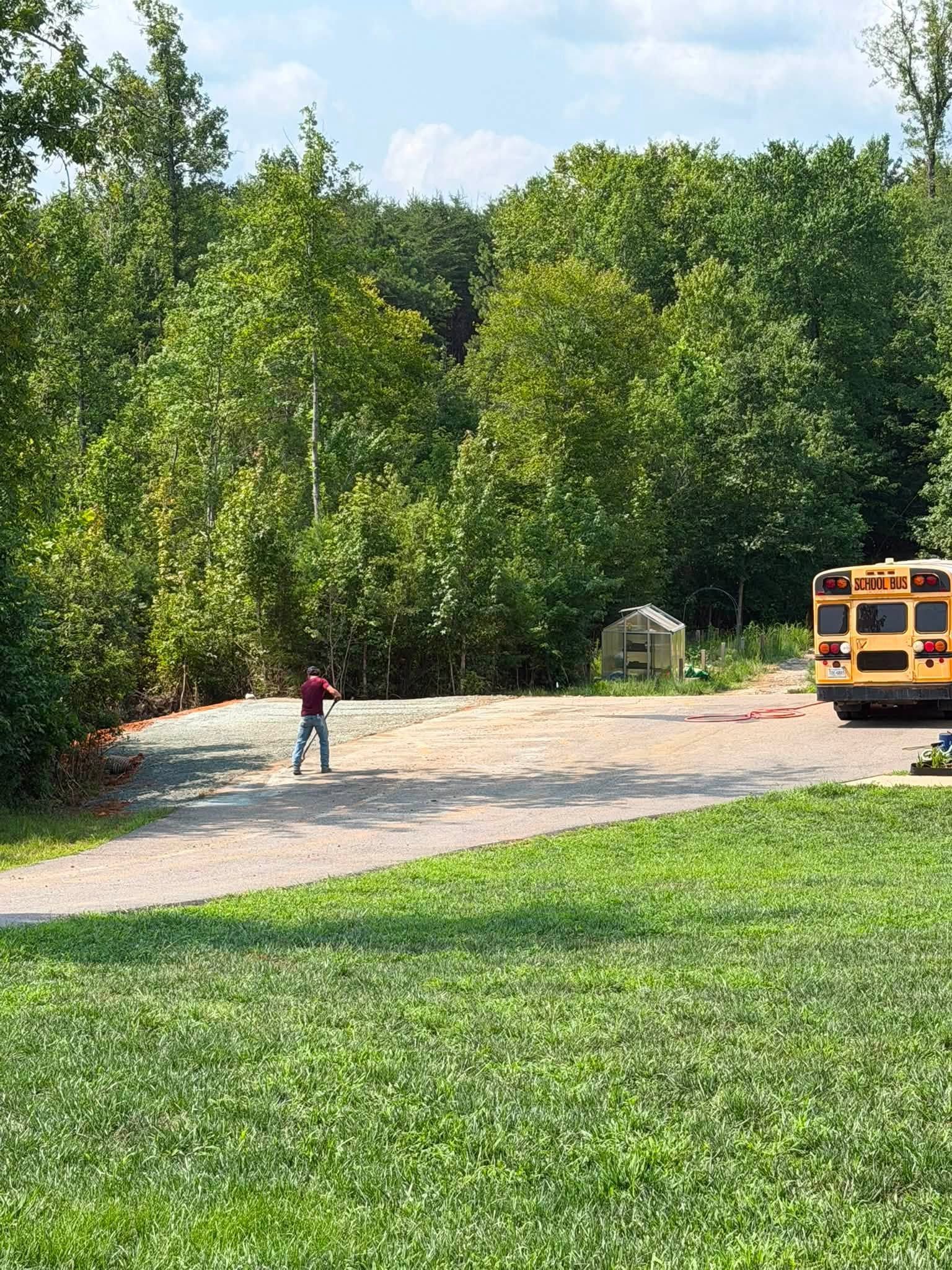 Child on gravel path beside school bus in a wooded park area