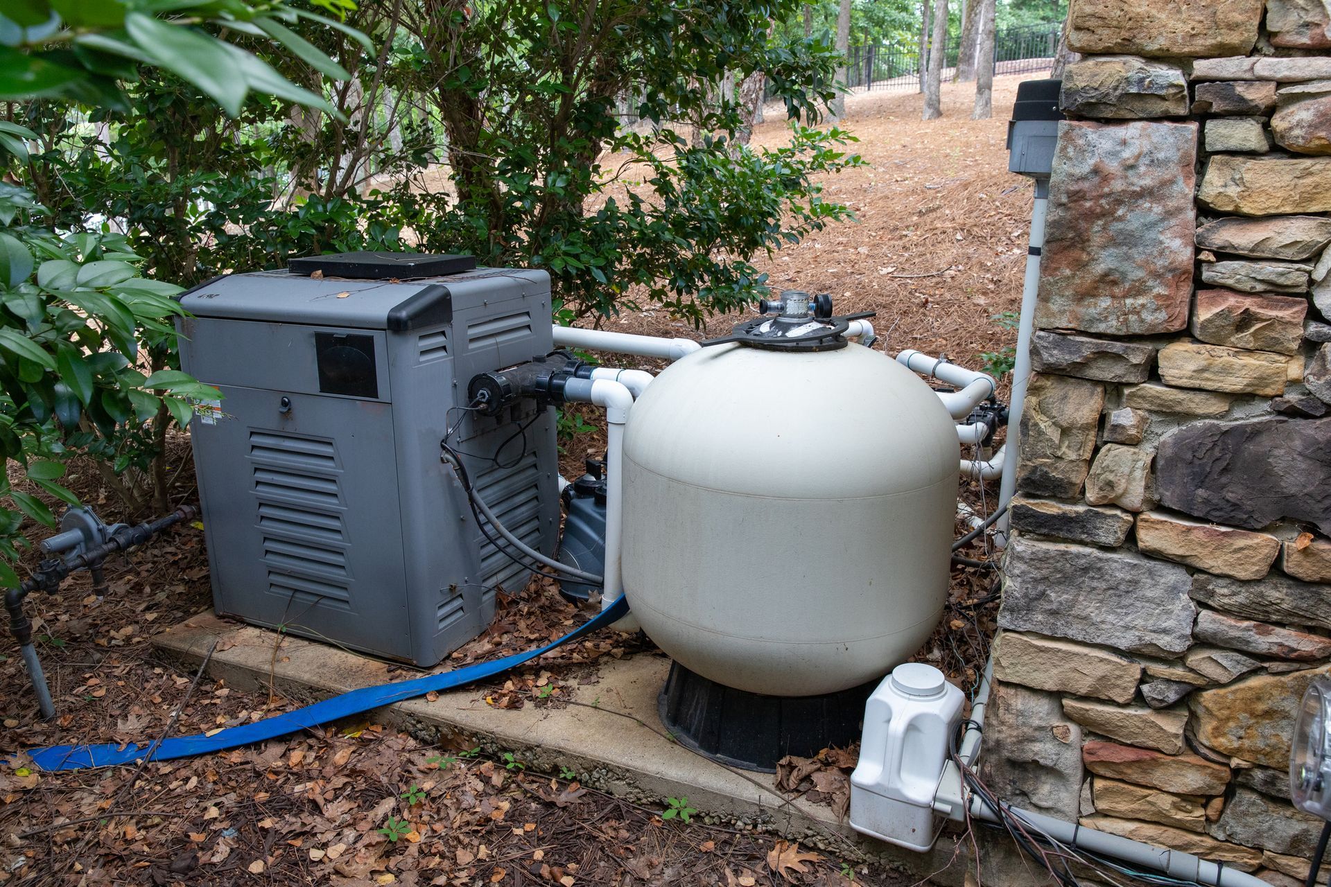 A swimming pool filter is sitting next to a stone wall.
