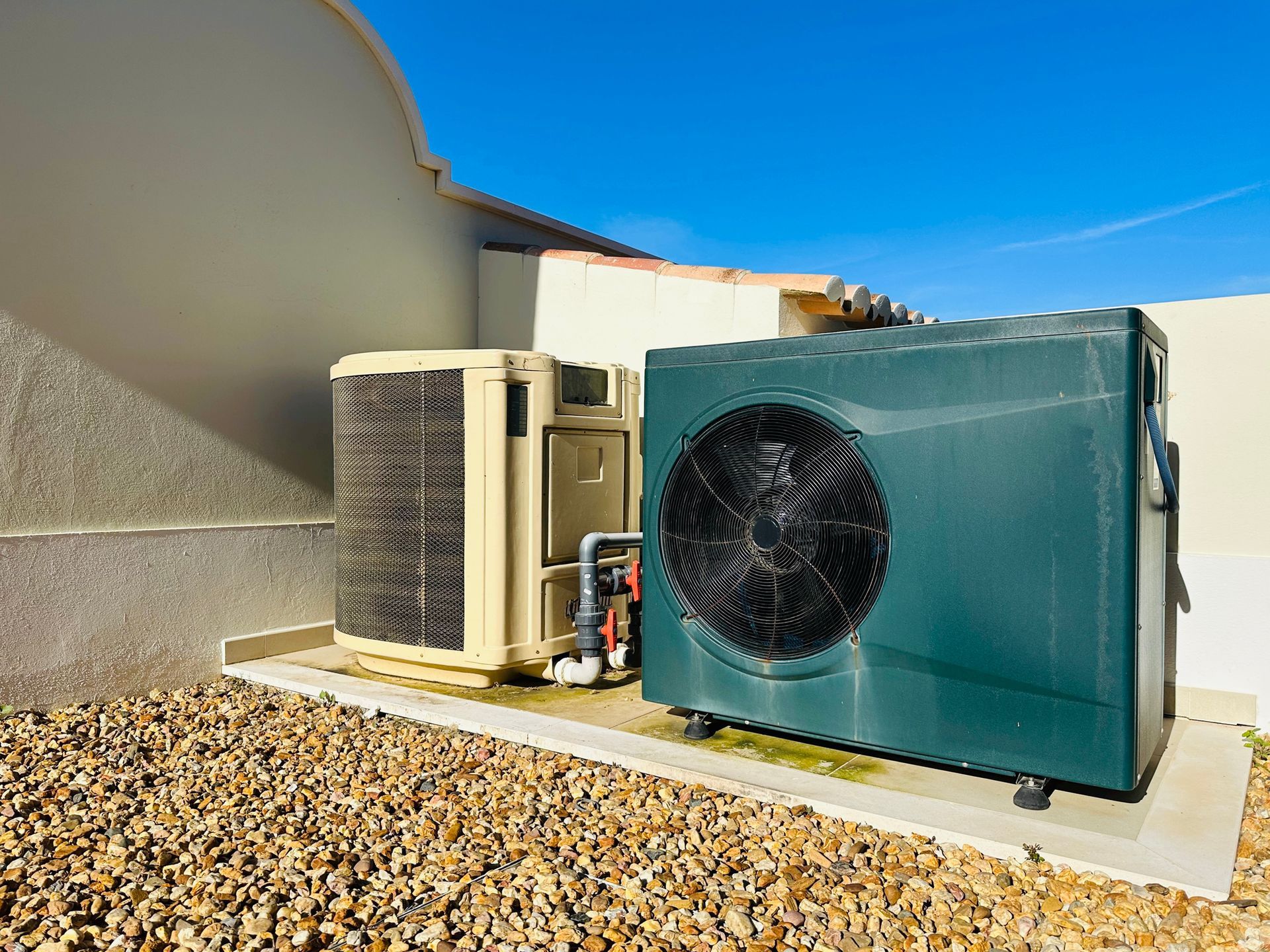 Two air conditioners are sitting next to each other on the side of a building.