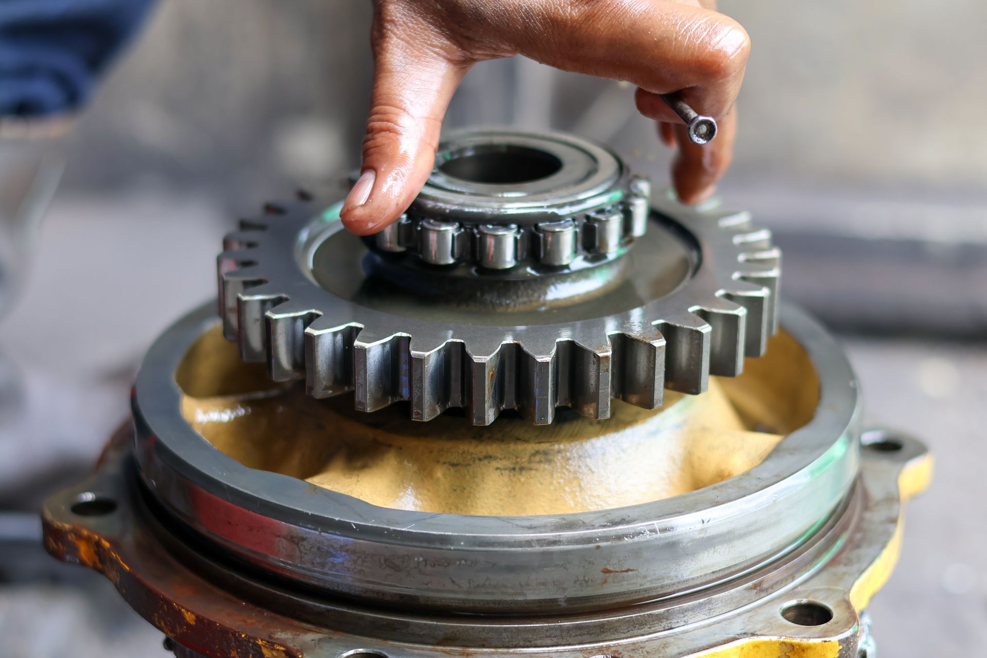 Close-up of a mechanic's hand installing a large planetary gear and a roller bearing assembly Close-up of a mechanic's hand installing a large planetary gear and a roller bearing assembly