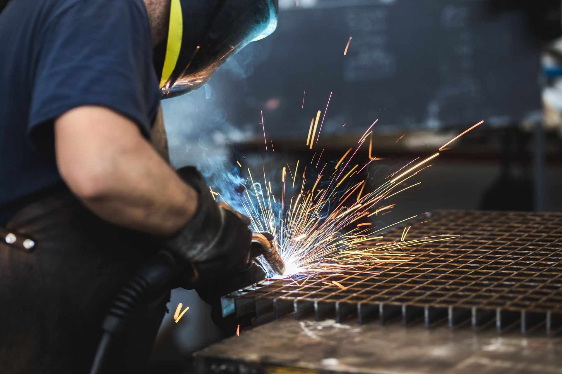 Industrial worker uses torch on metal with blurry background, representing welding repair services.