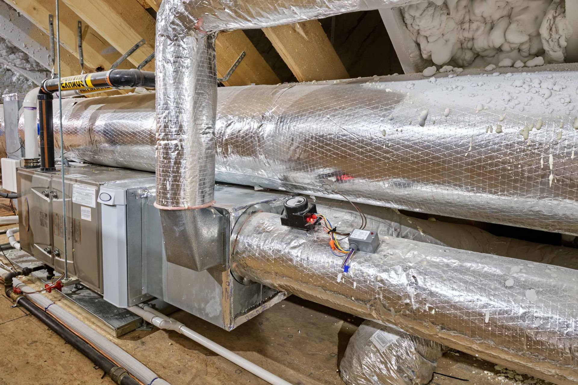 Foil-wrapped HVAC ducts and insulated pipes in an industrial utility room