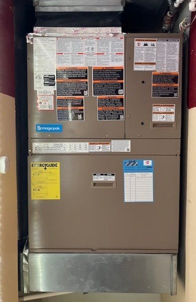 Gray industrial electrical panel with warning labels and ductwork above and below.