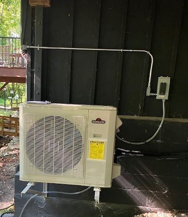 Technician servicing rooftop HVAC unit with tools and gauges beside a large fan unit
