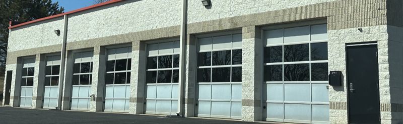 Exterior of a gray industrial building with large garage doors and windows under a red roofline | Bob's Main Street Auto & Towing