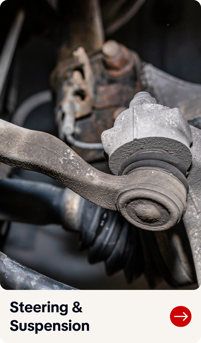 Close-up of a worn car steering suspension joint with rust and grime, labeled “Steering & Suspension.” | Bob's Main Street Auto & Towing