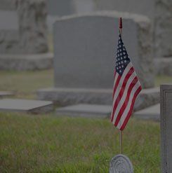 An american flag is sitting on top of a grave in a cemetery.