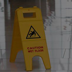 A yellow caution wet floor sign is sitting on a tiled floor.