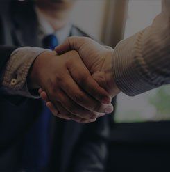 A man in a suit and tie is shaking hands with another man.