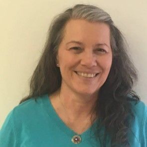 A woman in a blue shirt is smiling for the camera.