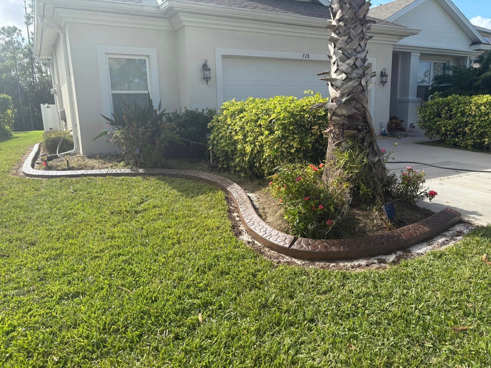 A white house with a lush green lawn and a palm tree in front of it.