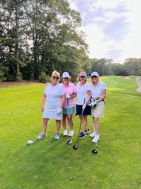 A group of people are standing on a golf course talking to each other.