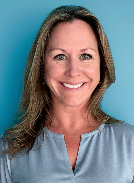 A woman in a blue shirt is smiling in front of a blue background.