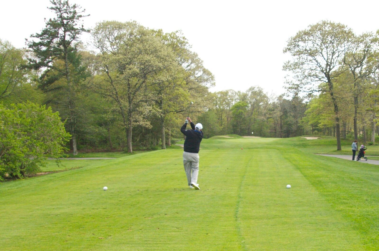 A man is swinging a golf club on a golf course