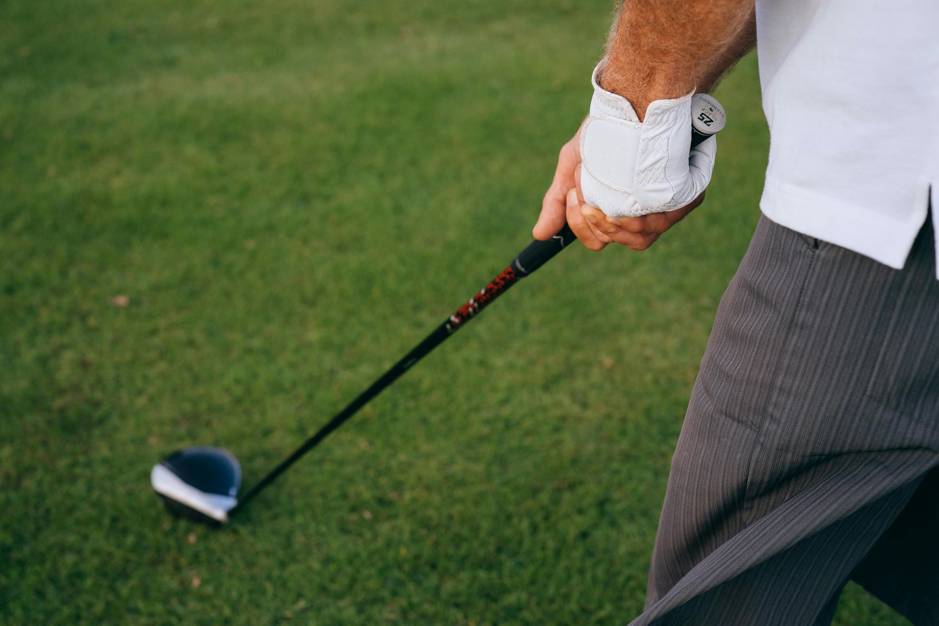 A man is swinging a golf club on a golf course.