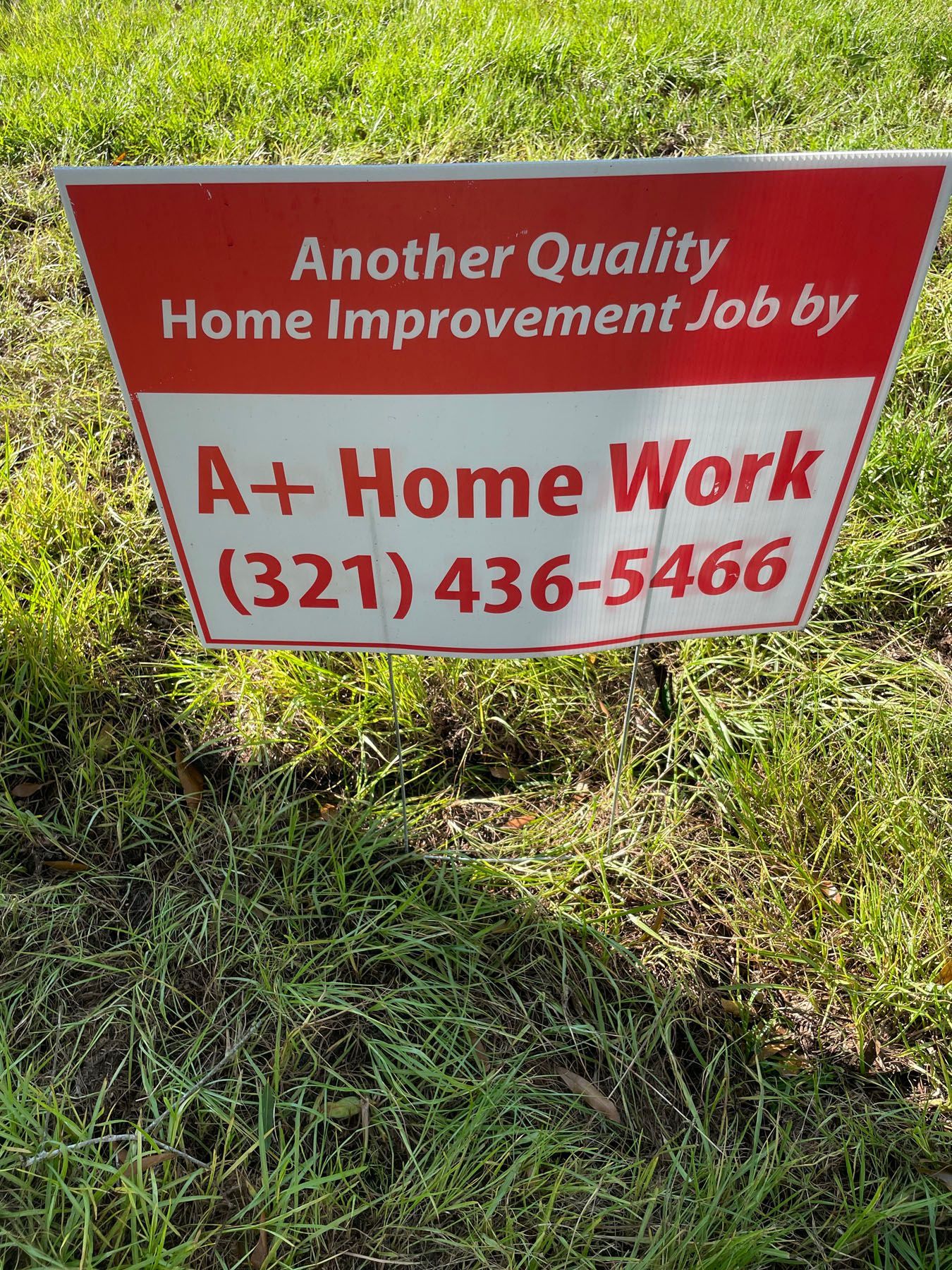 A red and white sign on a lawn advertising 