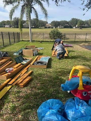 a group of people are working on a playground in a backyard .