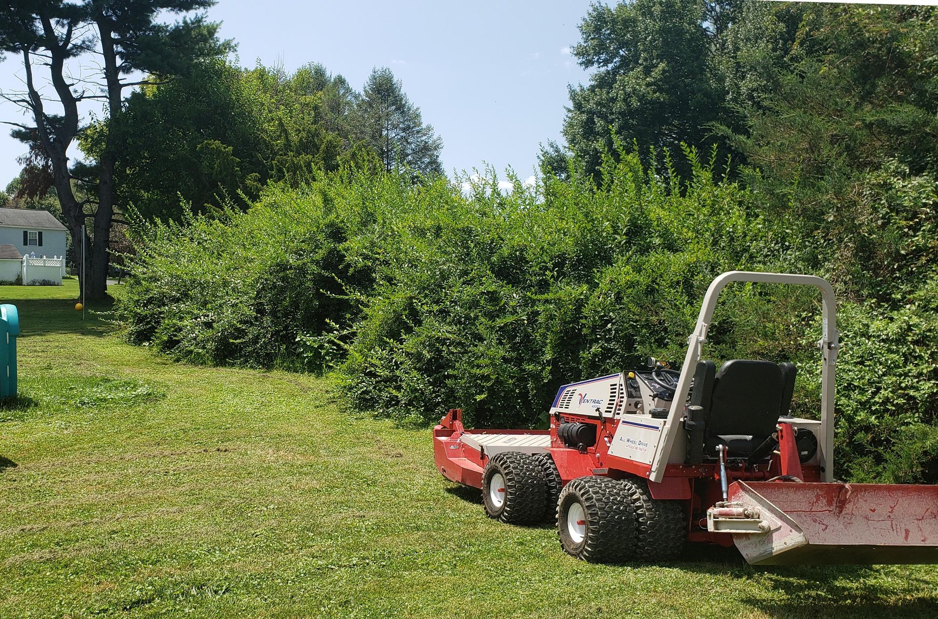 A red and white lawn mower is parked in a grassy field