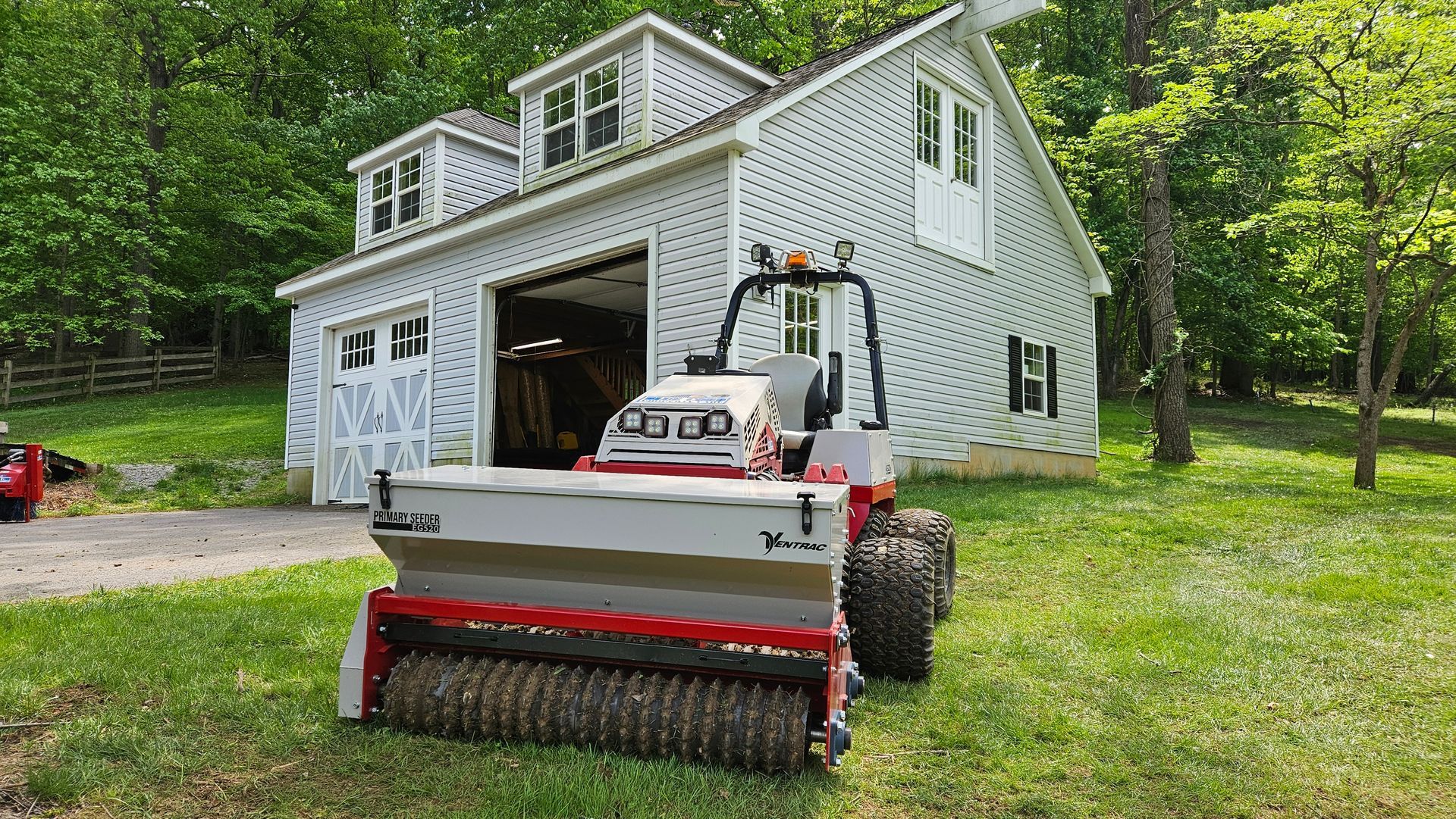 A lawn mower is parked in front of a white house.