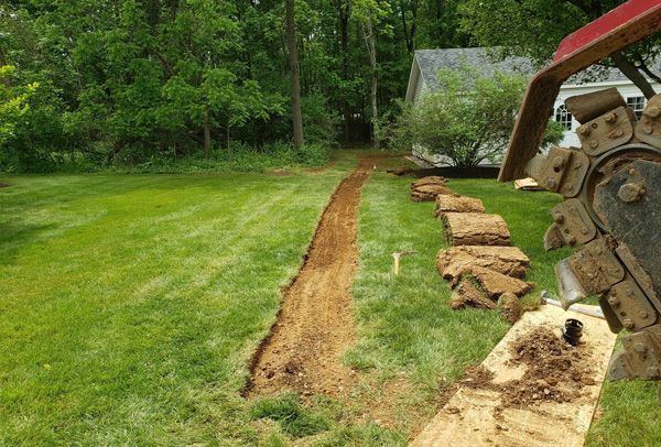 A trencher is being used to dig a path in a yard.